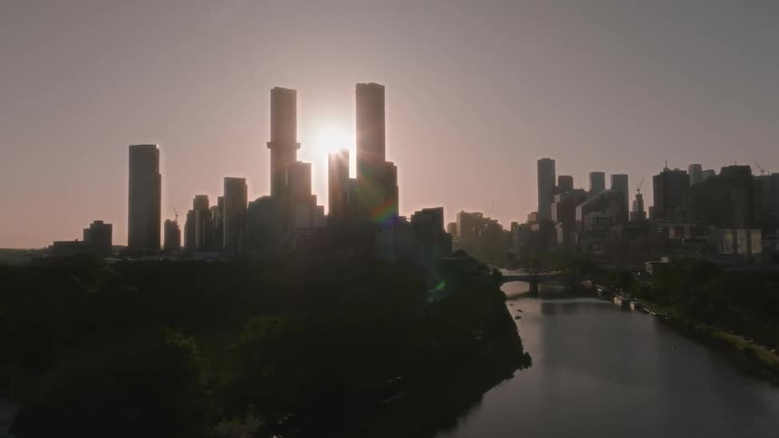 River cuts through city as bright sun casts skyscrapers into silhouette
