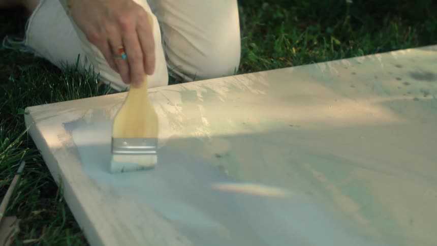 A female is painting on a canvas outdoors