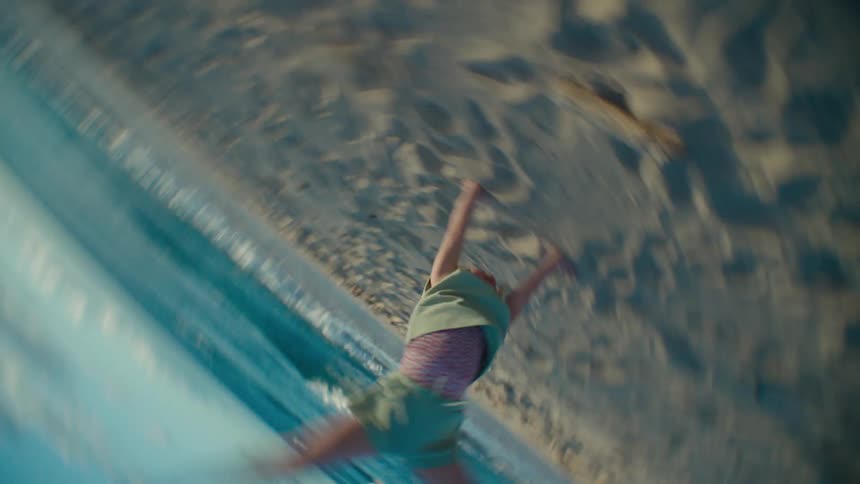 Blonde girl turns a cartwheel on the beach near the sea
