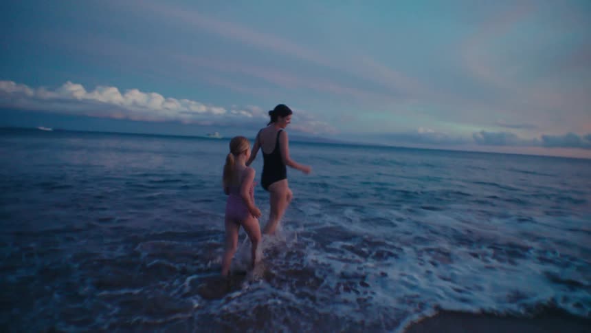 A woman and her daughter run into the ocean