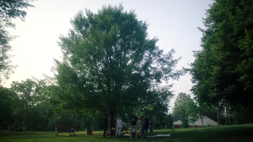 A group of men stand in a circle in a park
