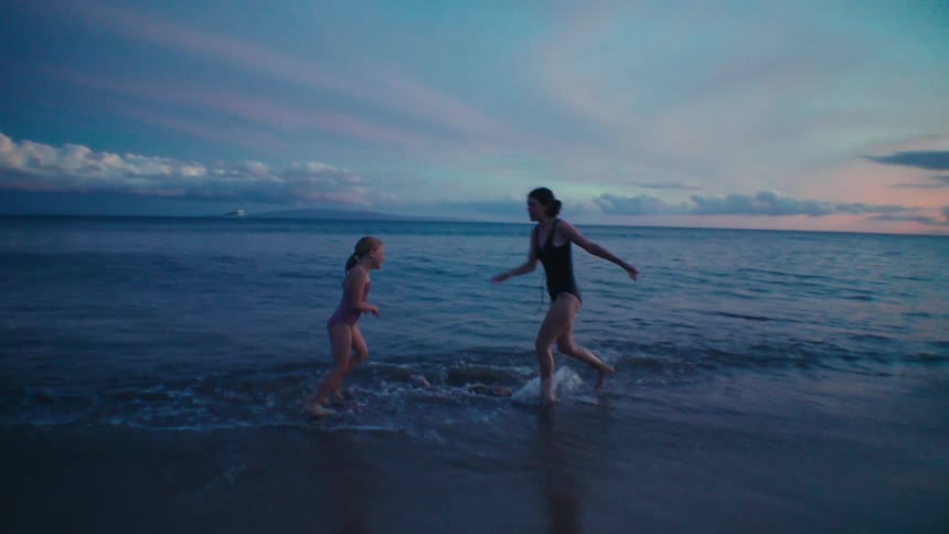 A mother and daughter chase each other around on the beach