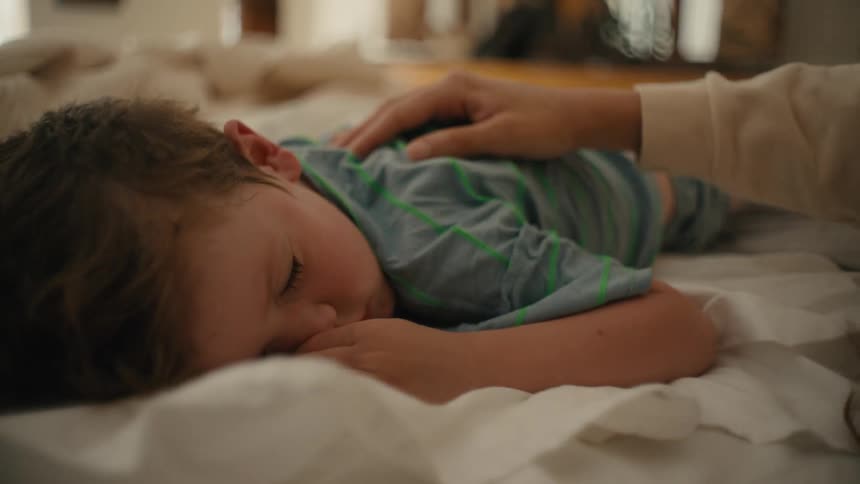 Mother with white sweatshirt touches back of her son