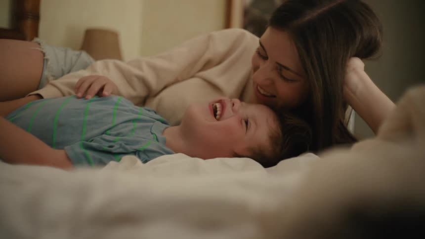 A mother and son talk in bed