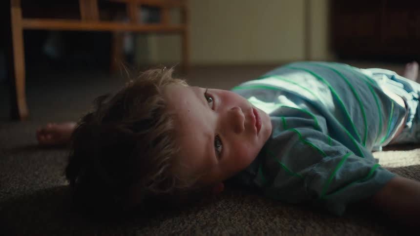 A young boy lying on the floor looking up and thinking