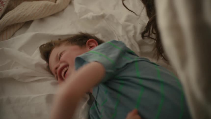 A mother and son play around in bed
