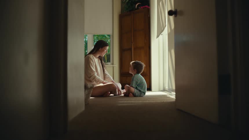 A mother is sitting with her son talking at the end of the hall