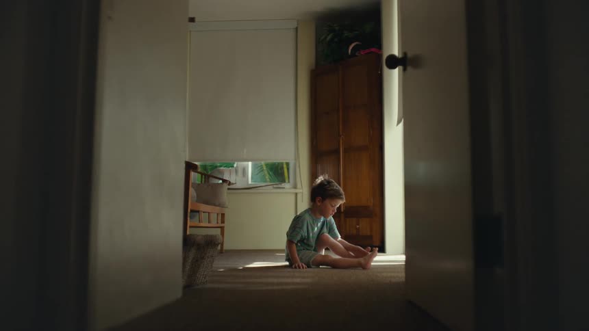 A child is sitting at the end of the hallway