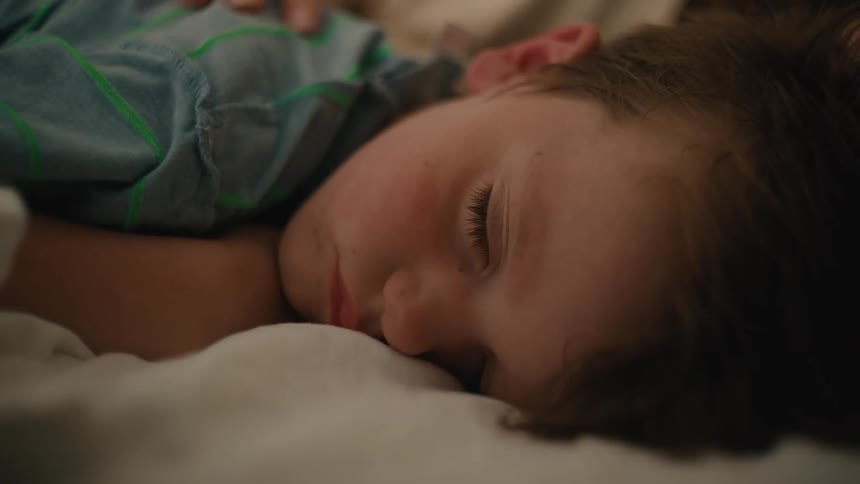 Mother strokes the head of her son lying on bed
