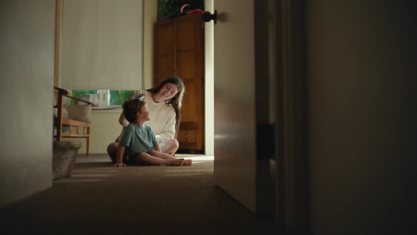 A mother brushing her kids hair on the floor of their home