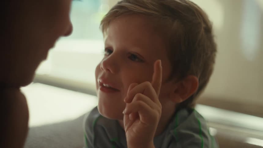 Boy smiles and taps his mother on the nose