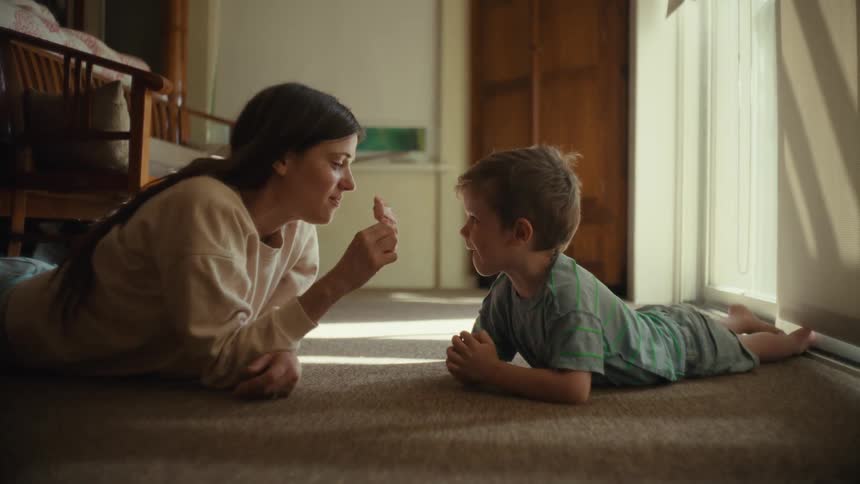 Mother and son lying on carpet share a popsicle