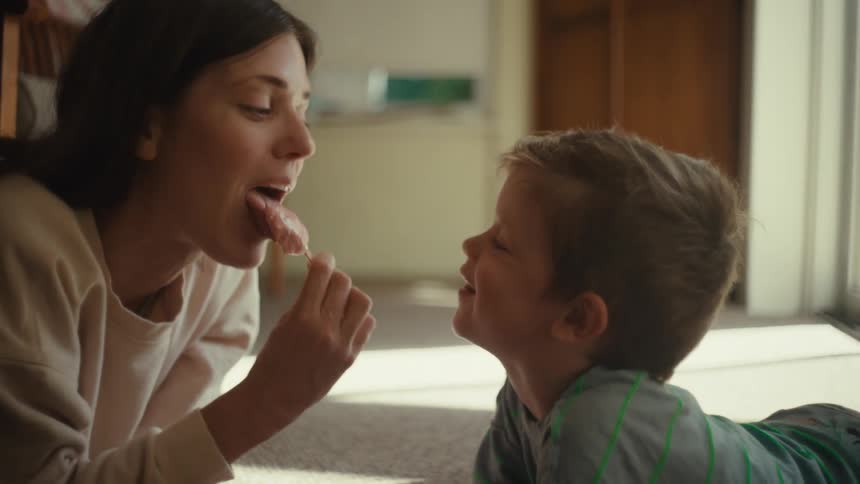 Mother and son share ice cream lying on the floor
