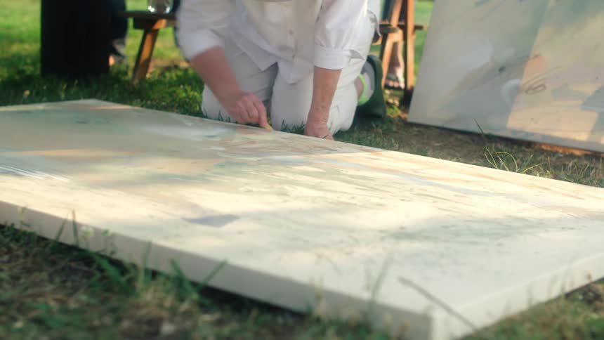 People move around as artist works on canvas lying on lawn