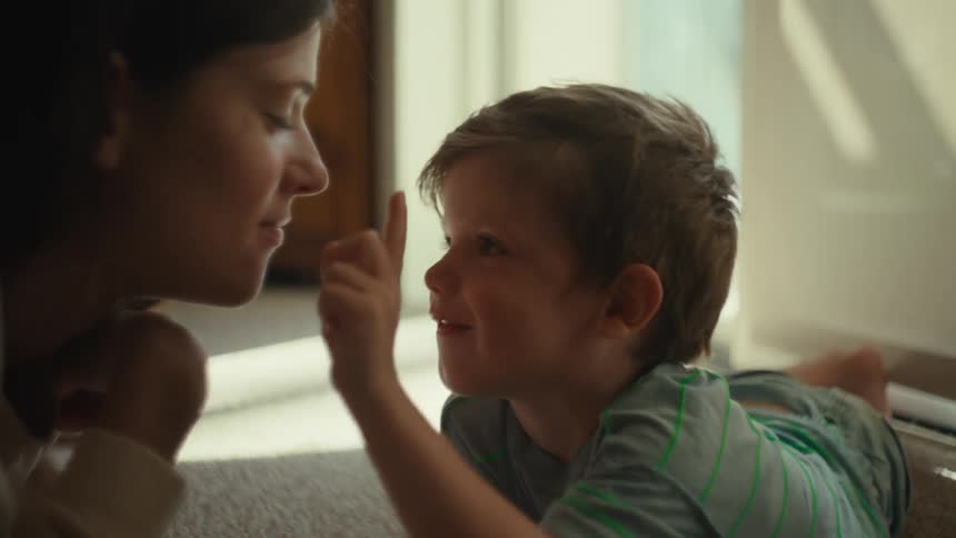 Mother and child touching noses while lying on the floor