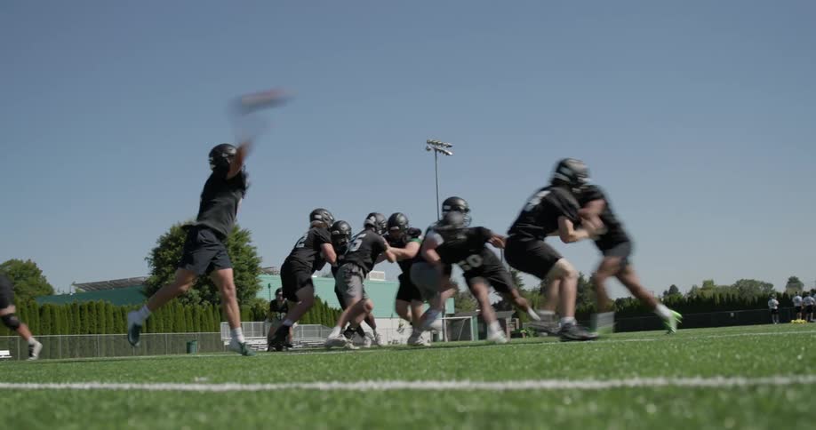 Football players play across football field under a clear blue sky
