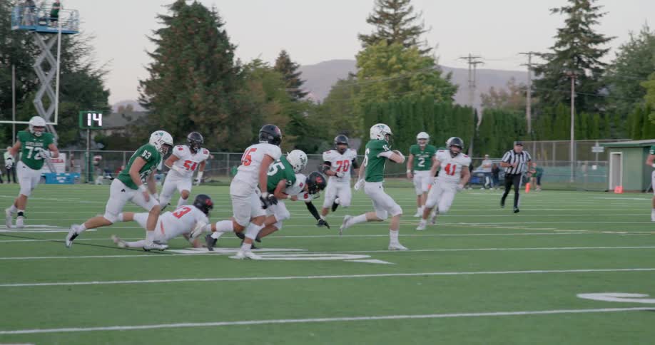 Athlete runs from defenders during high school football game