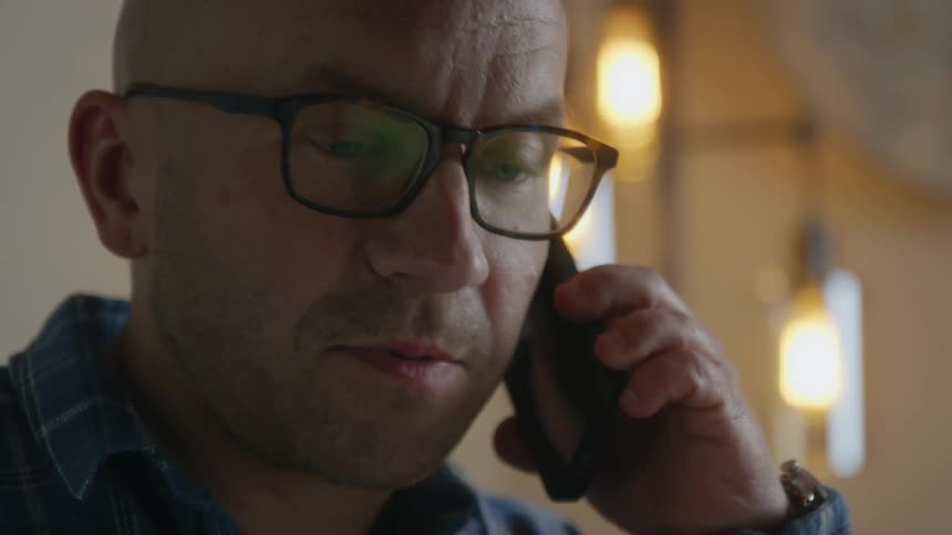 Man talks on smartphone in room lit by wall lamps