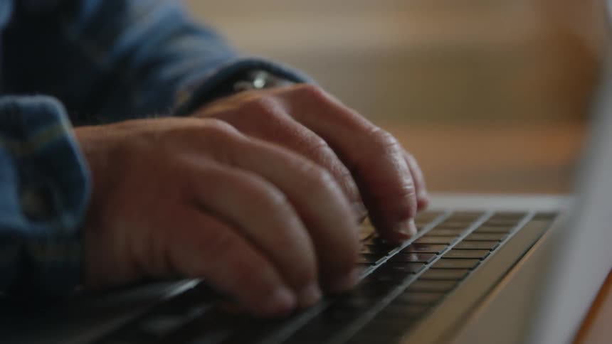 A man types on his laptop