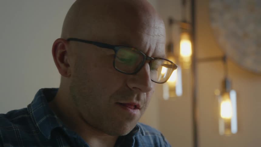 A man works in front of a bright lamp