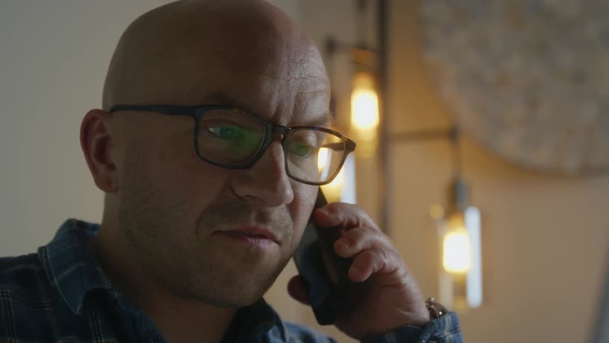 A man talks on the phone at home