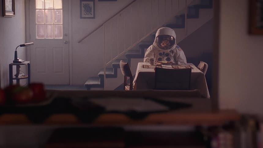 A person wearing an astronaut suit sitting in a room