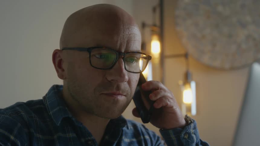 Man loses his smile and nods seriously while on phone call