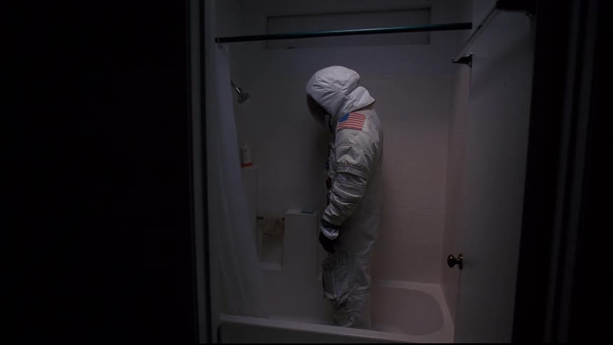 A person in a spacesuit stands in a shower