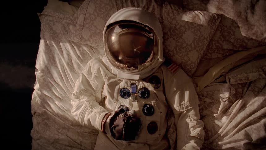 A person in a space suit lies in bed