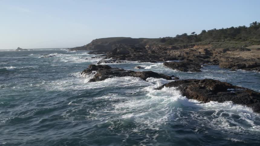 Large waves crash onto rocks along the coast