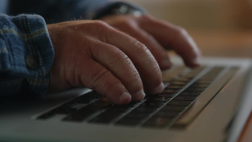 Man with small hands types on laptop