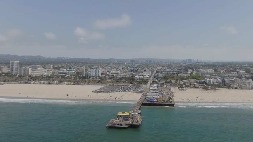 Long walkway leads to pier just off beach a long distance from skyline and mountains