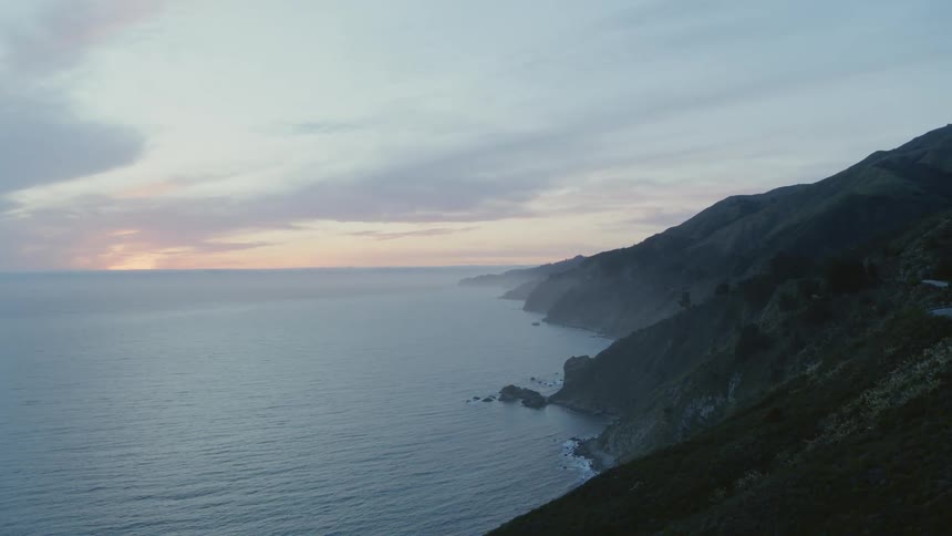 Gentle waves roll below mountains on the coast