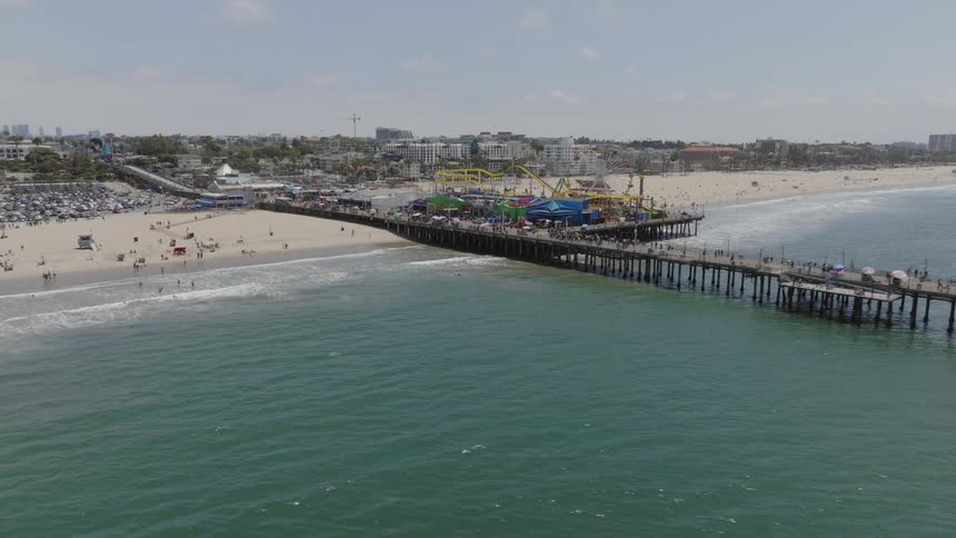 People move across beach and through carnival a long distance from city skyline