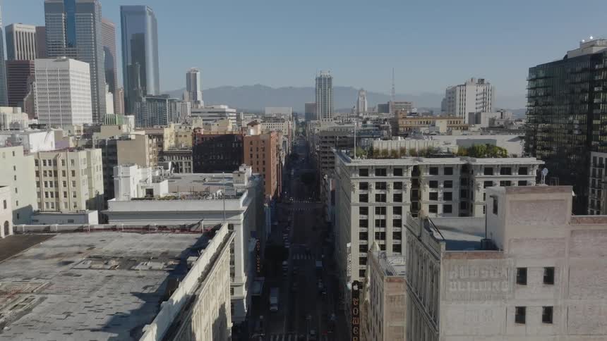 Street leads through apartment buildings near downtown skyscraperstoward foggy mountains on the horizon
