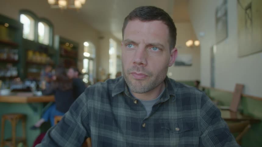 Man sits at table in restaurant and writes something with a pencil