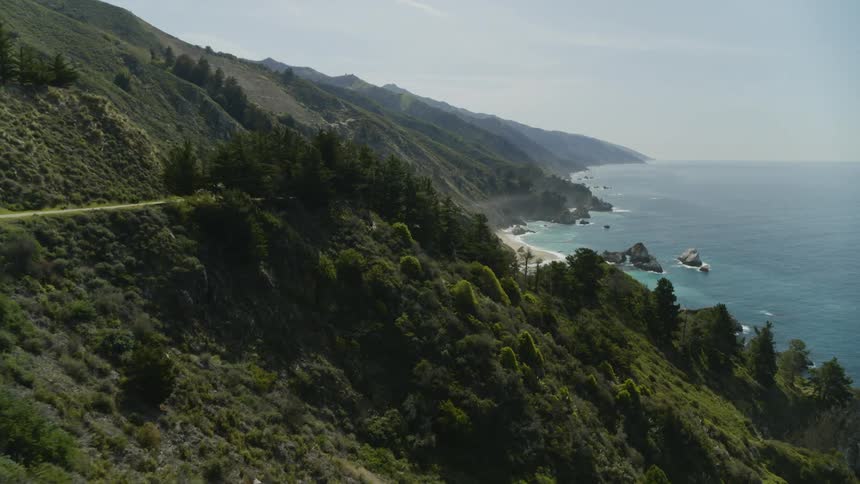 Highway passes parking lot overlooking slope leading to ocean