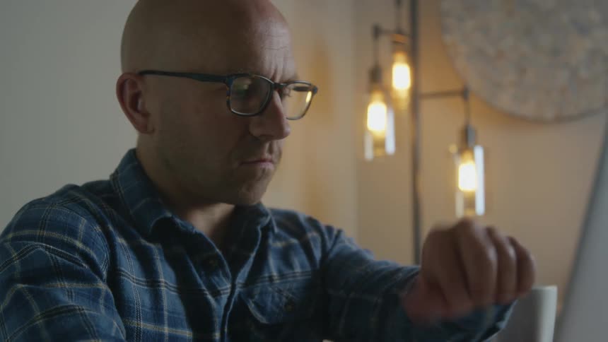 Man briefly stops typing to check his wristwatch