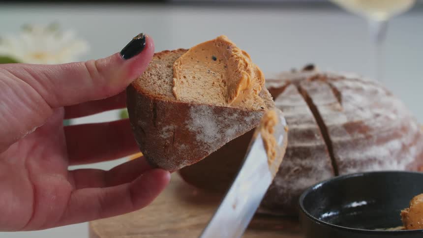 A person spreads peanut butter on the bread