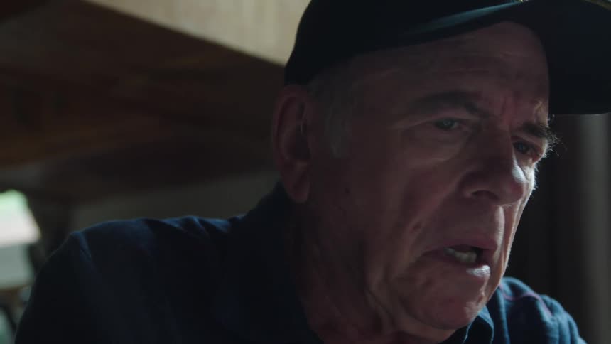 Elderly man frowns and shakes his head in disbelief