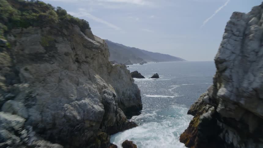 Aerial view of rocky shoreline near the ocean on a sunny day