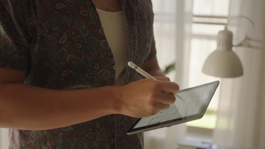 A person using a tablet with house plans on it in a room