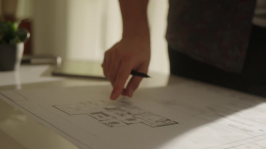 Two people stand around table discussing floor plan