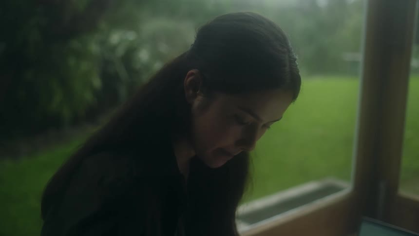 A woman is looking at something on her porch