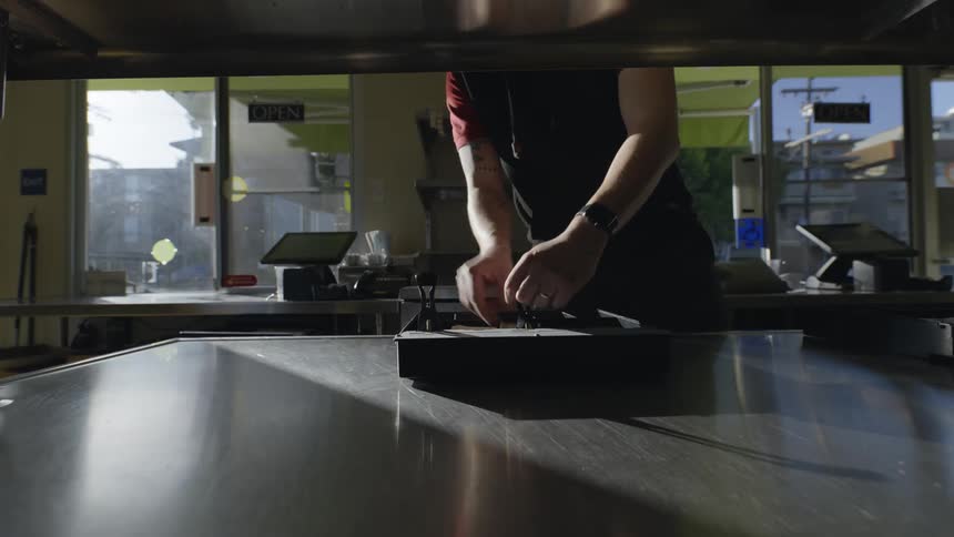 The employee is adding money to the till