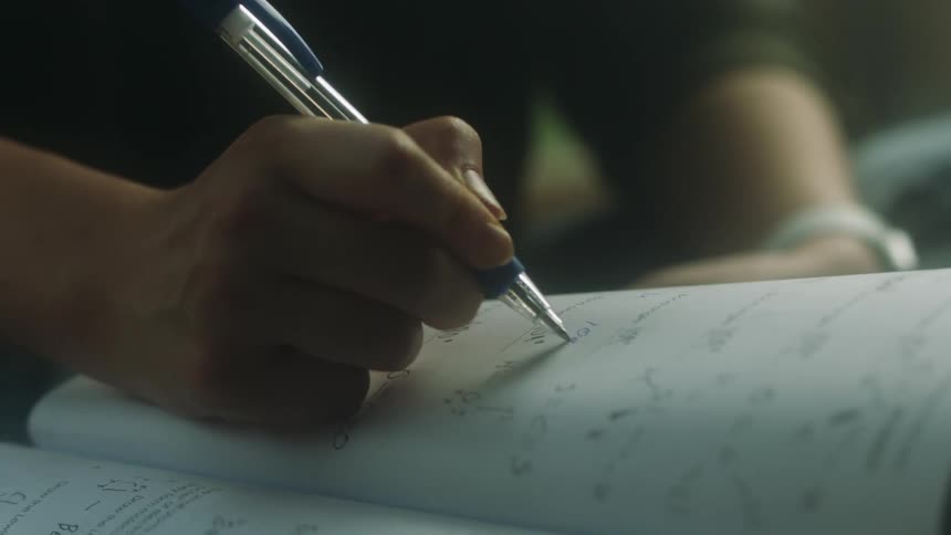 A person is doing math problems in a notebook