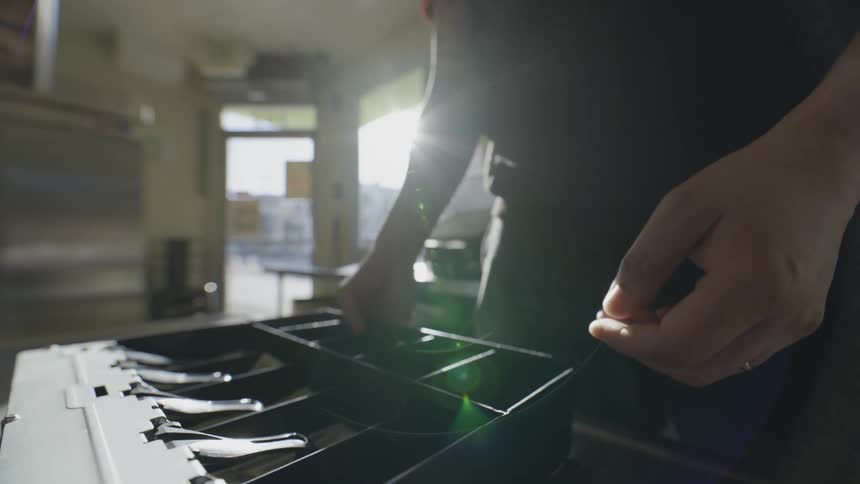 A man putting away a cash register drawer in a restaurant
