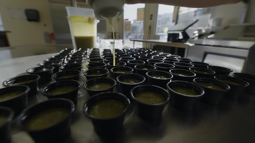 The employee is filling the small cups with sauce