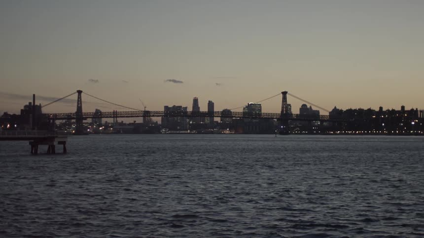 Behind the bridge is a city at sunset