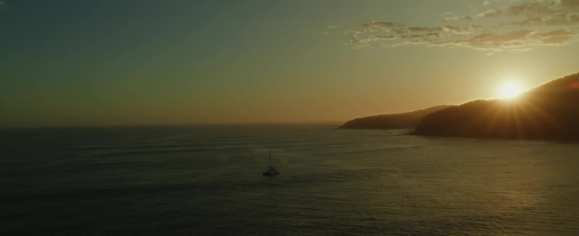 Aerial view of sun setting over the mountains next to the ocean